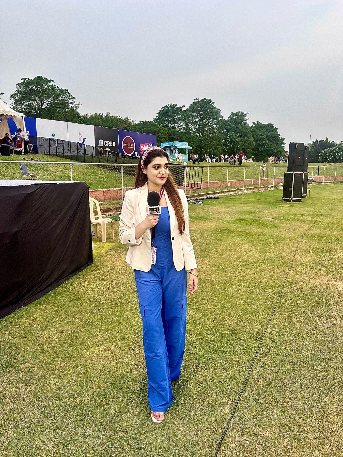 Khushi Ansari walking the outfield with a microphone at the International Legends Championship